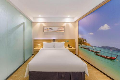 a bedroom with a large bed and a painting of a boat at GreenTree Alliance Hotel Shenzhen Yantian District Dameisha in Shenzhen
