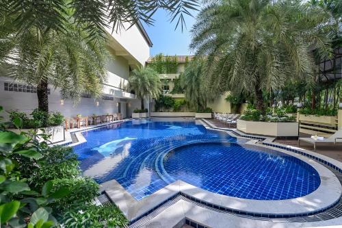 a swimming pool in a courtyard with palm trees at Elong Hotel Pattaya Jomtien Beach in Na Jomtien