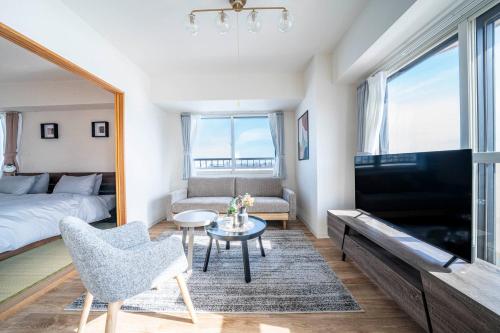 a bedroom with a bed and a living room with a tv at E-US Naebo 601 in Sapporo