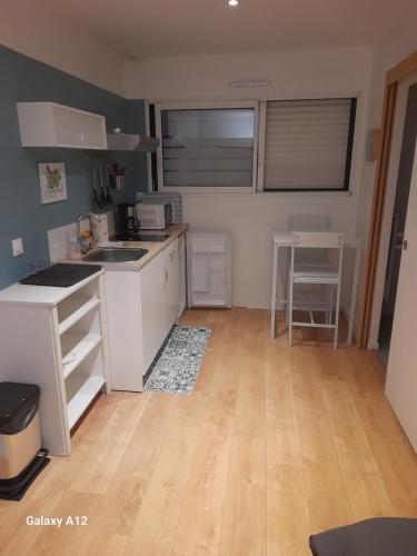 une cuisine avec des armoires blanches et un plancher en bois dans l'établissement Appartement indépendant Broceliande, à Saint-Thurial