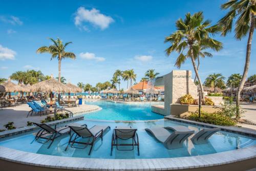 a pool at the resort with chairs and palm trees at Playa Linda Beach Resort in Palm-Eagle Beach