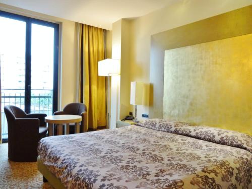 トレッツァーノ・スル・ナヴィーリオにあるホテル ティファニー ミラノのベッド、テーブル、椅子が備わるホテルルームです。