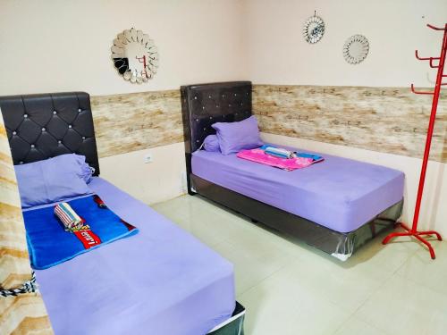 two beds in a room with purple sheets at Nuwono Tasya Syariah in Bandar Lampung