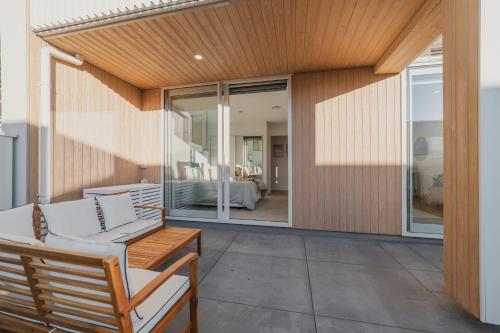 Un patio con muebles blancos y una puerta corrediza de vidrio. en Central 1BR Apartment with Kitchen & Patio, en Christchurch