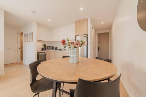 una mesa de comedor con sillas y un jarrón de flores en Central 1BR Apartment with Kitchen & Patio, en Christchurch