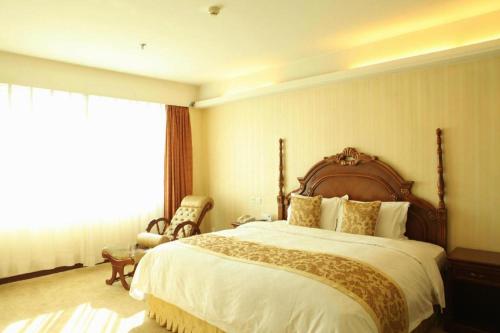 a bedroom with a large bed and a chair at Yanji Yanbian International Hotel in Yanji