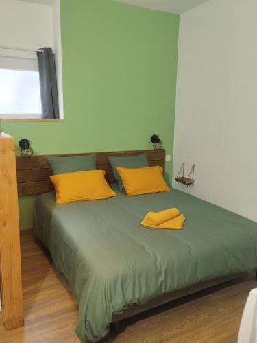 une chambre avec un lit avec des oreillers jaunes dessus dans l'établissement Le petit cozy, à La Roche-Chalais