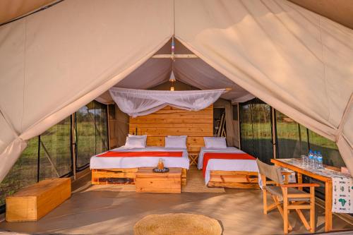 a bedroom in a tent with two beds and a table at Pamoja Serengeti Luxury Camp in Serengeti National Park