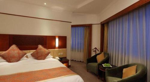a hotel room with a bed and two chairs at Capital Hotel in Beijing