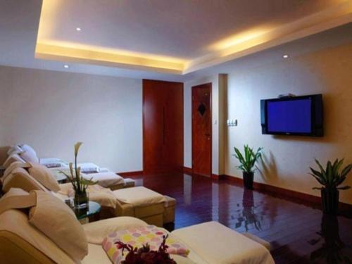 a living room with couches and a flat screen tv at New Century Hotel Taizhou 