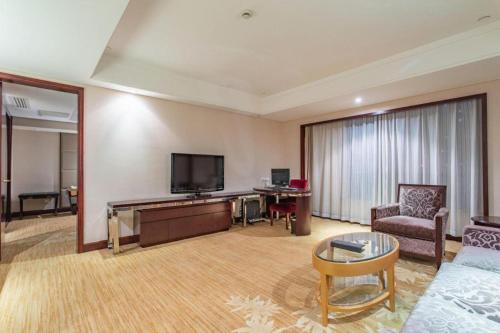 a living room with a couch and a flat screen tv at Hohhot Hai Liang Plaza Hotel in Hohhot