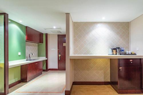 a kitchen with green and brown walls and a counter at Hohhot Hai Liang Plaza Hotel in Hohhot