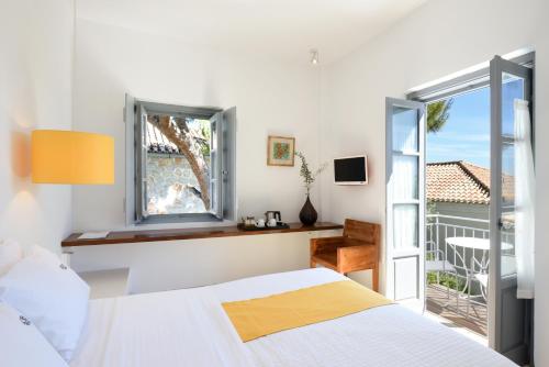 a bedroom with a bed and a window and a balcony at Orloff Resort in Spetses