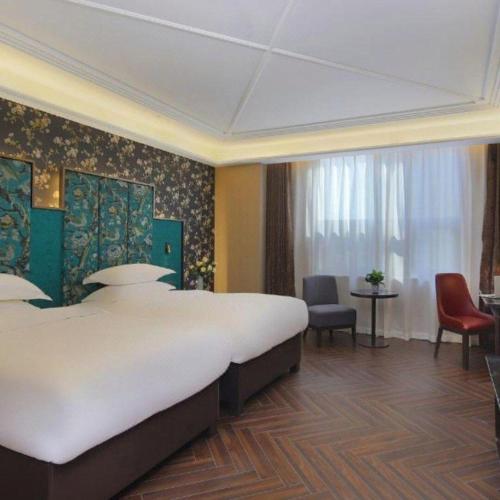a hotel room with a large bed and chairs at Jinjiang Metropolo Hotel - Taizhou Wanda Plaza in Taizhou