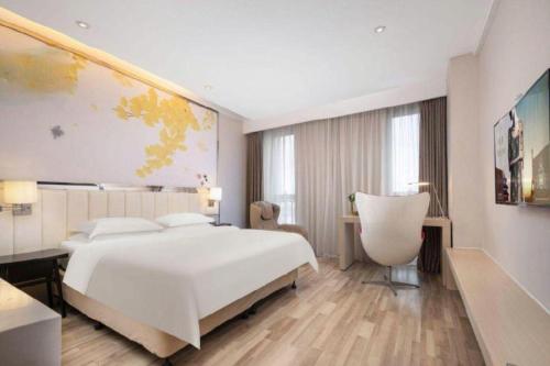 a bedroom with a large white bed and a chair at Jinjiang Metropolo Hotel - Taizhou Wanda Plaza in Taizhou