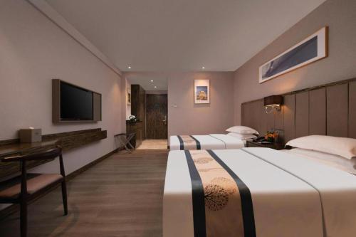 a hotel room with two beds and a television at Landmark Hotel in Zhuhai