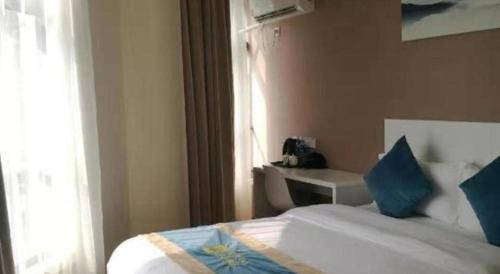 a bedroom with a bed with blue pillows and a window at Shell Shanghai Songjiang District Xinqiao Town Xinqiao Hotel in Chunshen