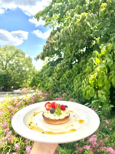 a person holding a plate with a cake with strawberries on it at Best Western Hotel Ile de France in Château-Thierry