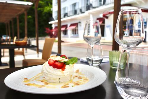 a plate with a dessert on a table with wine glasses at Best Western Hotel Ile de France in Château-Thierry