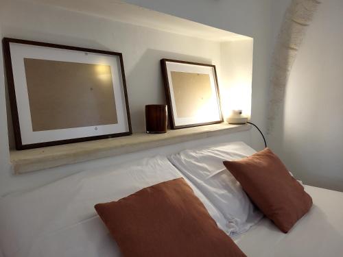 two pictures on a shelf above a white couch at Dimora La Piana in Ostuni