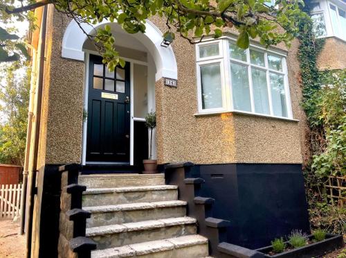 a house with a black door and stairs at Lye Vally Headington- Oxford in Oxford