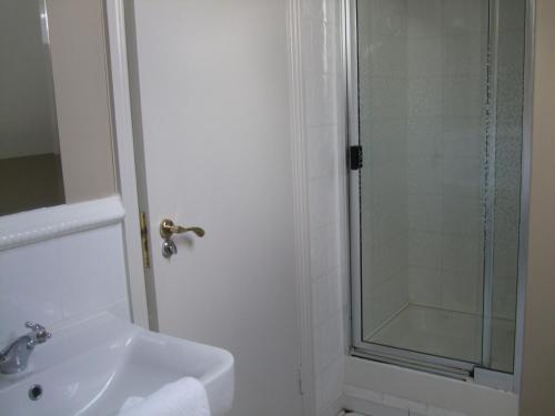 a white bathroom with a shower and a sink at Harmony Inn - Glena House in Killarney