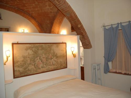 1 dormitorio con una pintura en la pared sobre una cama en Monolocale a Buonconvento, en Buonconvento