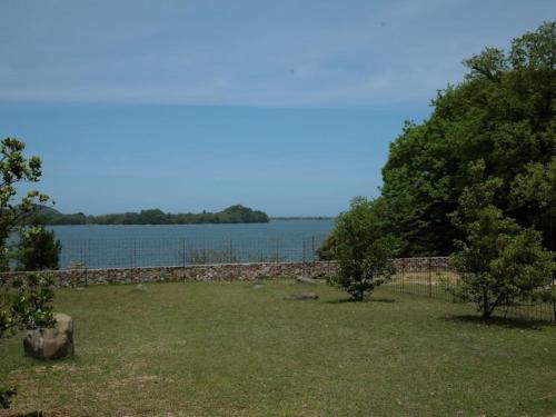 a yard with a stone wall and a lake at HOTEL HOLIDAY HOME in Kyotango
