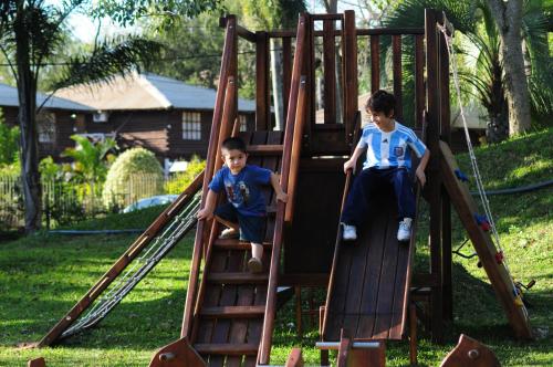 Dois rapazes num escorrega num parque infantil. em Río Arriba Suites & Apartments & Restó em Bella Vista