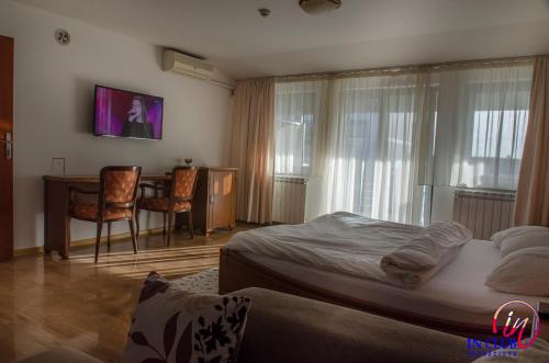 a bedroom with a bed and a desk and a table at Apartment and Rooms In Club in Inđija