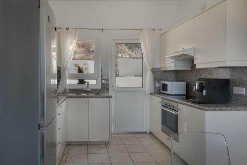 a white kitchen with white cabinets and a sink at Phaedrus Living Seaview Hilltop Maisonette in Chlorakas