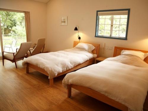 a room with two beds and a chair and a window at HOTEL HOLIDAY HOME in Kyotango