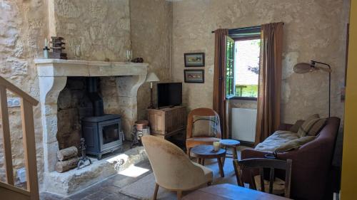 a living room with a fireplace and a couch and chair at Hameau des Galottières-Perche, immersion nature in Ceton