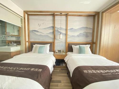 two beds in a room with a painting on the wall at Beijing Inner Mongolia Hotel Chaoyang in Beijing