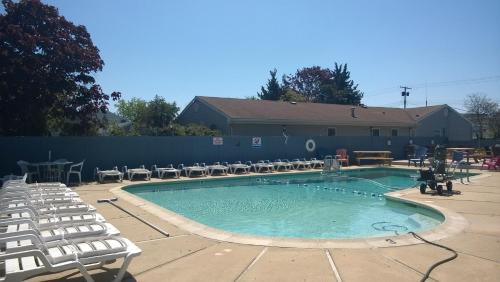 une grande piscine avec des chaises et une table dans l'établissement Atlantic Motel, à Point Pleasant Beach