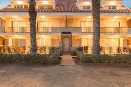 a building with two palm trees in front of it at Villa ao Mar in Santa Maria