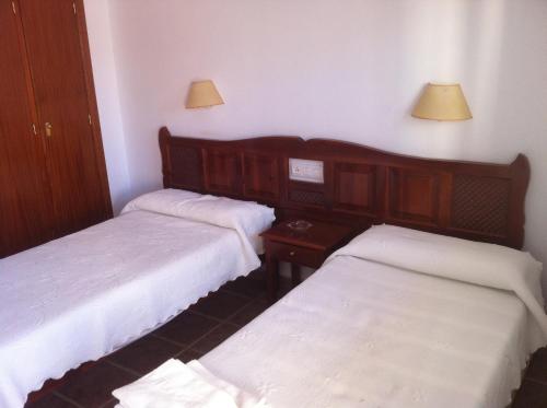Hostal Rios في بولونيا: غرفة بسريرين وطاولة ومصابيح