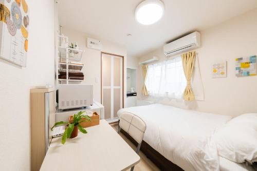 a small bedroom with two beds and a table at Parkside Shinjuku Tokyo in Tokyo