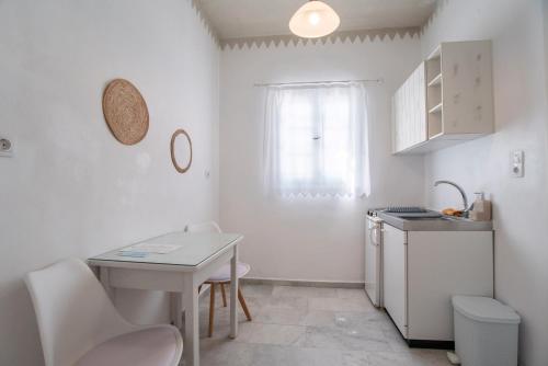 a small white kitchen with a table and a sink at Maroulis Studios Naxos in Mikri Vigla