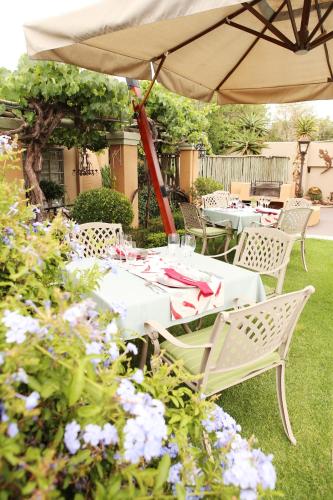 a table and chairs under an umbrella in a garden at Oleander Guest House in Kimberley