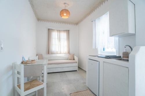 a white kitchen with a couch and a table at Maroulis Studios Naxos in Mikri Vigla