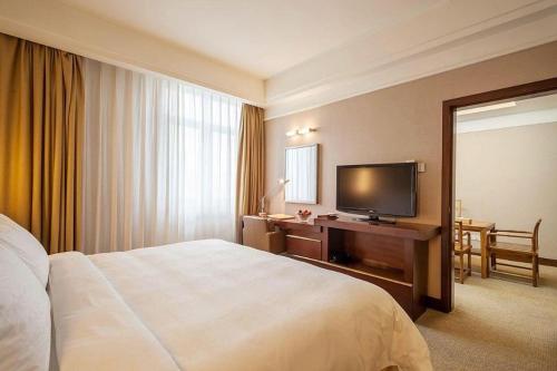a hotel room with a bed and a flat screen tv at Best Western Plus Fuzhou Fortune Hotel in Fuzhou