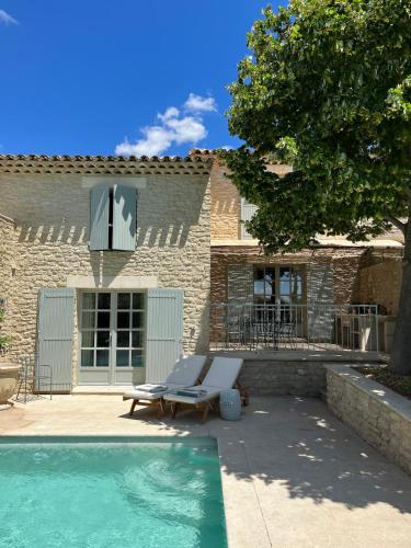 une piscine avec un fauteuil et une maison dans l'établissement Le Clos des Rosiers, a charming place in Gordes, à Gordes
