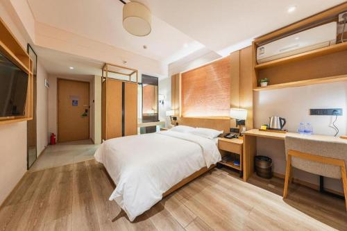 a bedroom with a large bed and a desk and a sink at V8 Ziyuangang Hotel in Guangzhou
