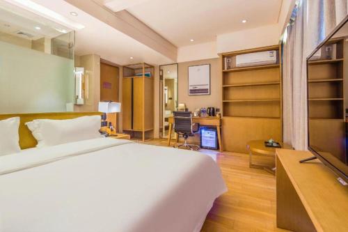 a bedroom with a bed and a desk and a television at V8 Ziyuangang Hotel in Guangzhou