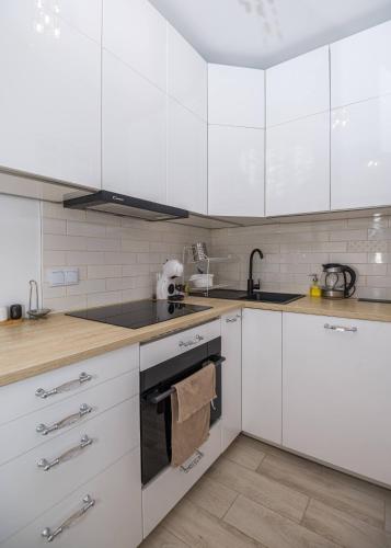 a white kitchen with white cabinets and a sink at Rezydencja Wrocław Legnicka in Wrocław