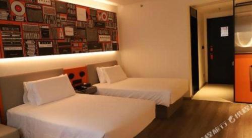 a hotel room with two beds and a wall with pictures at ibis Dongguan Dongcheng in Dongguan