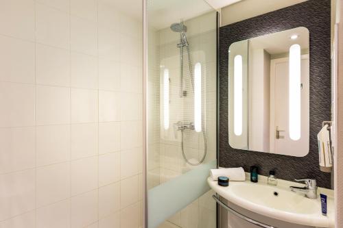 uma casa de banho branca com um lavatório e um espelho em ibis Roscoff em Roscoff