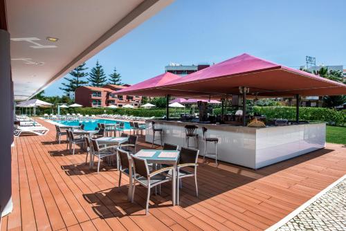 a patio with a bar and tables and chairs at Areias Village Beach Suite Hotel in Albufeira