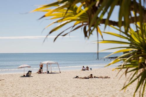 a group of people laying on the beach at Fairshore Noosa in Noosa Heads